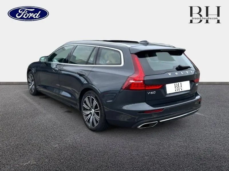 Vue 3/4 arrière droite d'une Volvo V60 T8 gris Savile métallisé avec feux arrière LED et double sortie d'échappement chromée.