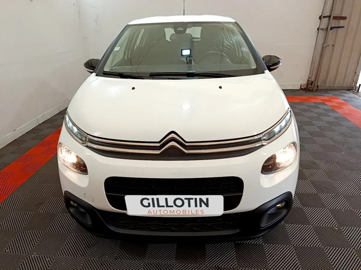 Citroën C3 blanche vue de face, phares allumés, avec calandre distinctive et plaque GILLOTIN AUTOMOBILES.