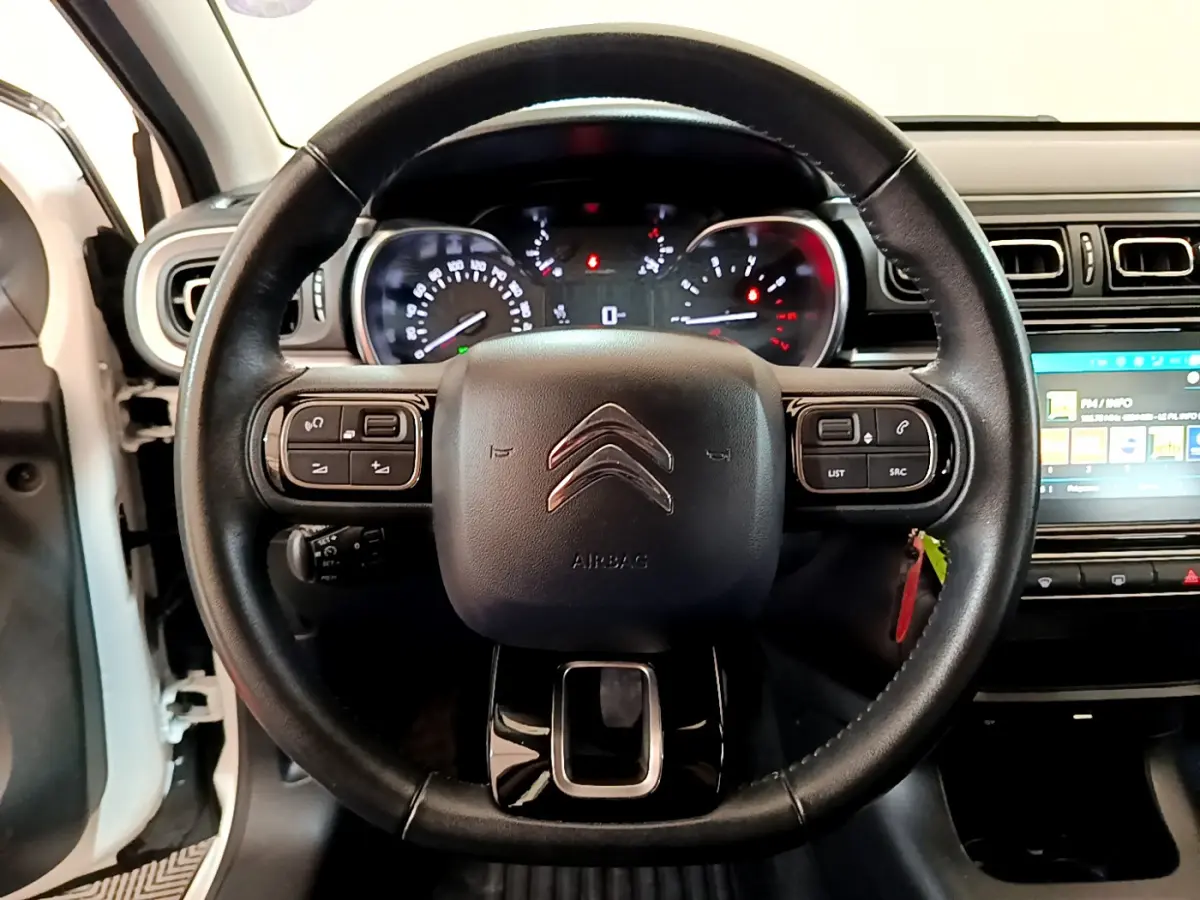 Vue rapprochée du volant cuir noir de la Citroën C3 blanche 2019 avec tableau de bord et écran tactile visible.