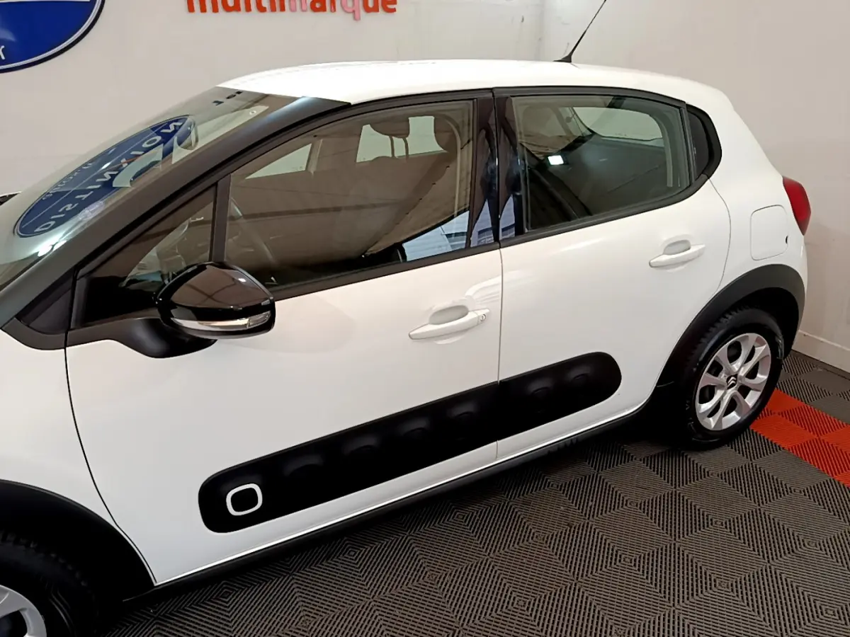 Profil côté gauche d'une Citroën C3 blanche avec protection noire sur les portières et rétroviseur noir brillant.