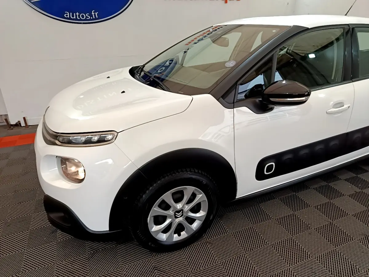 Vue 3/4 avant gauche d'une Citroën C3 blanche avec protections latérales noires et jantes alliage argentées.