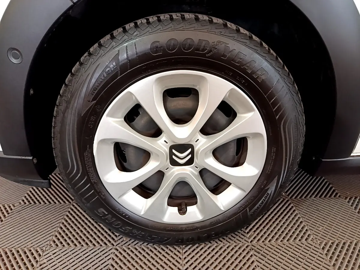 Gros plan sur la roue avant gauche d'une Citroën C3 blanche, jante alliage et pneu Goodyear visibles.