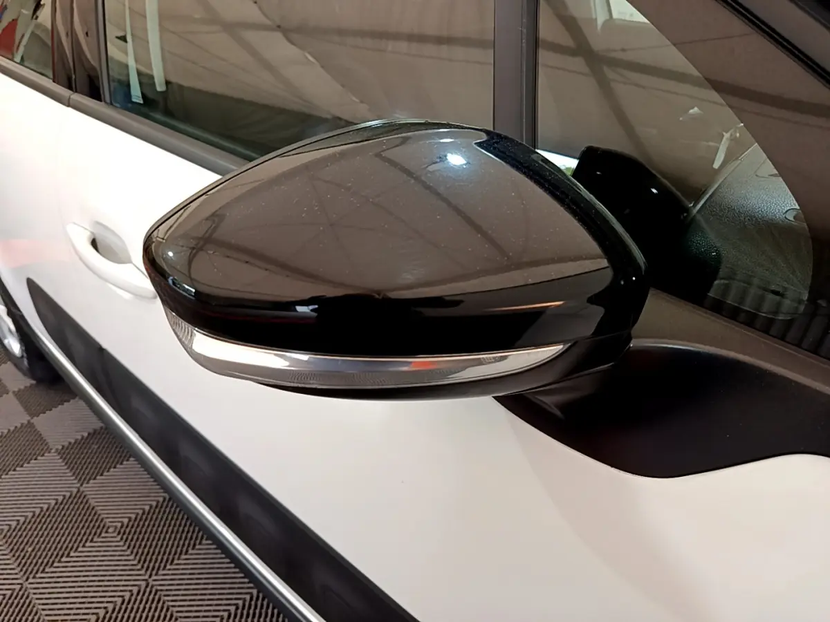 Rétroviseur noir avec clignotant intégré côté gauche sur Citroën C3 blanche vue de près en intérieur.