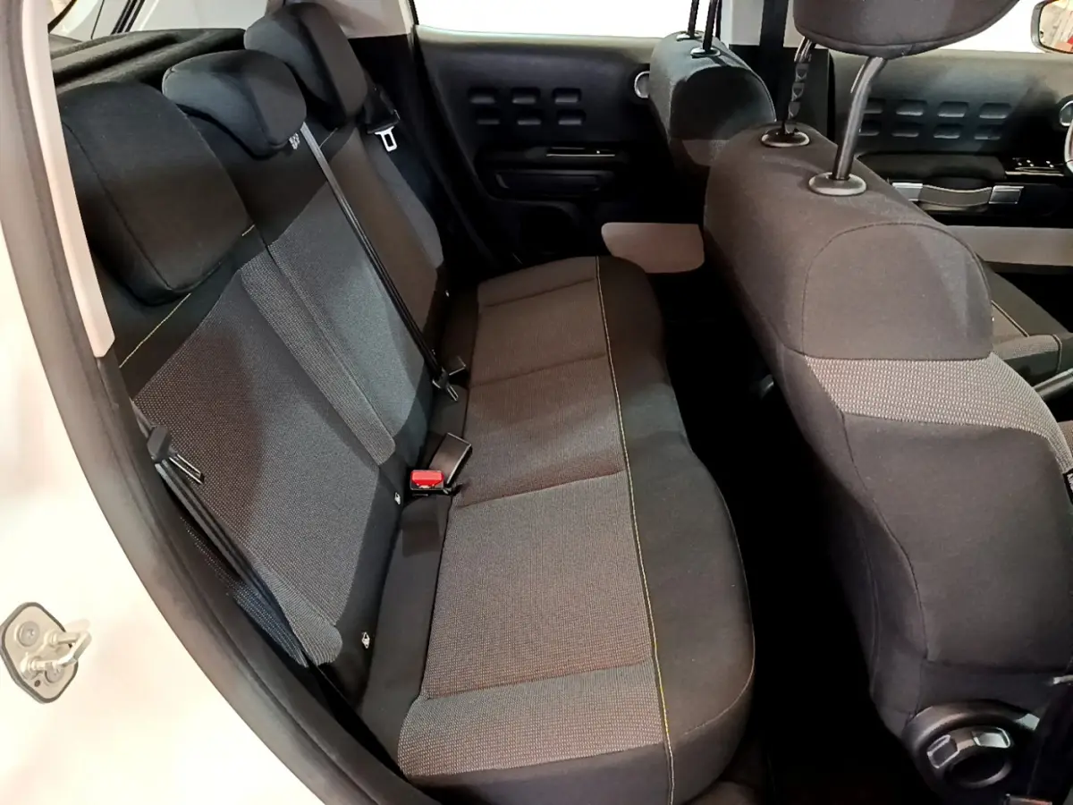 Vue intérieure côté gauche sur la banquette arrière noire et grise de la Citroën C3 blanche de 2019 avec appuie-têtes.