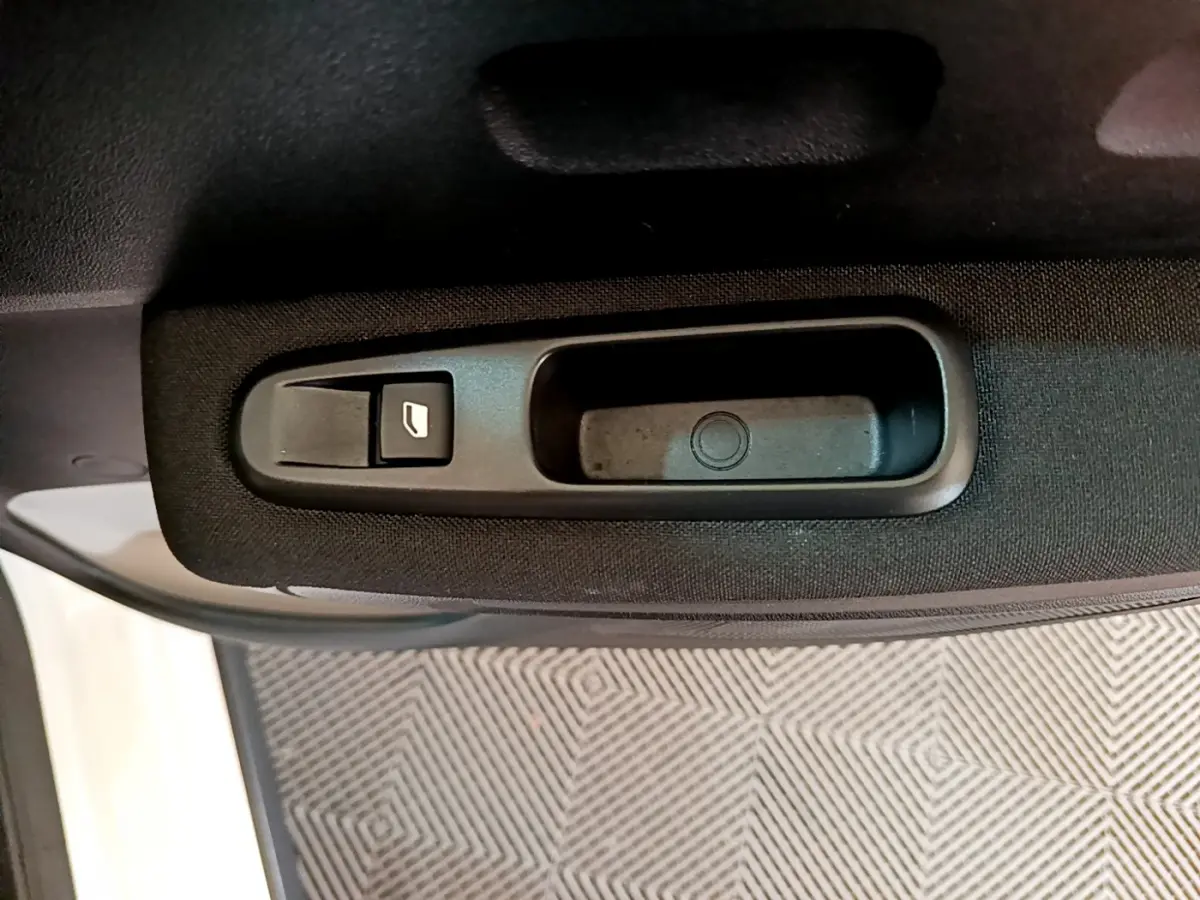 Gros plan sur la poignée intérieure noire et le bouton de lève-vitre côté gauche d'une Citroën C3 blanche de 2019.