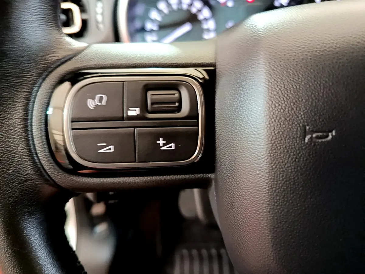 Gros plan sur les commandes gauche du volant cuir de la Citroën C3 blanche, version PureTech 110 Shine Business.