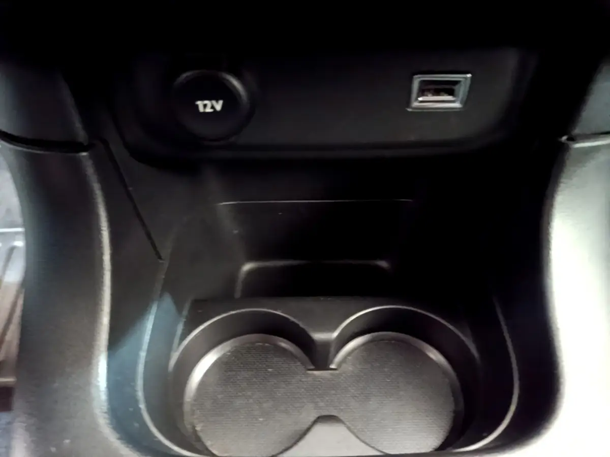 Gros plan sur le porte-gobelets noir et prises 12V et USB dans l'habitacle de la Citroën C3 blanche de 2019.