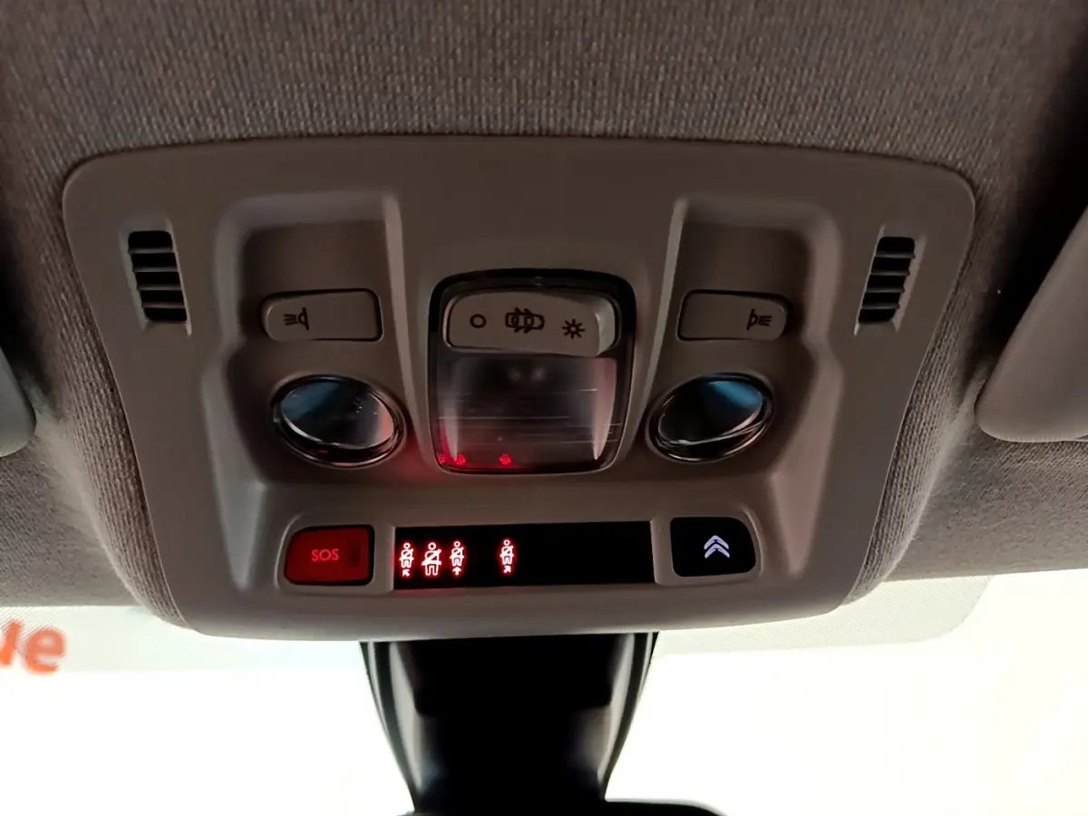 Vue en gros plan du plafonnier intérieur de la Citroën C3 blanche avec boutons SOS et éclairage intégré.