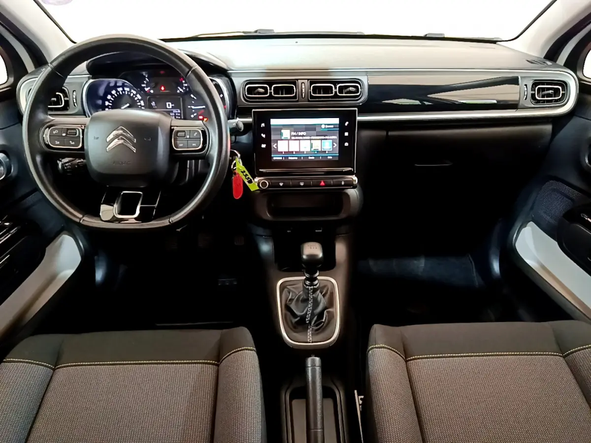 Intérieur de la Citroën C3 2019 vue de face, tableau de bord noir avec écran tactile central et volant cuir multifonctions.