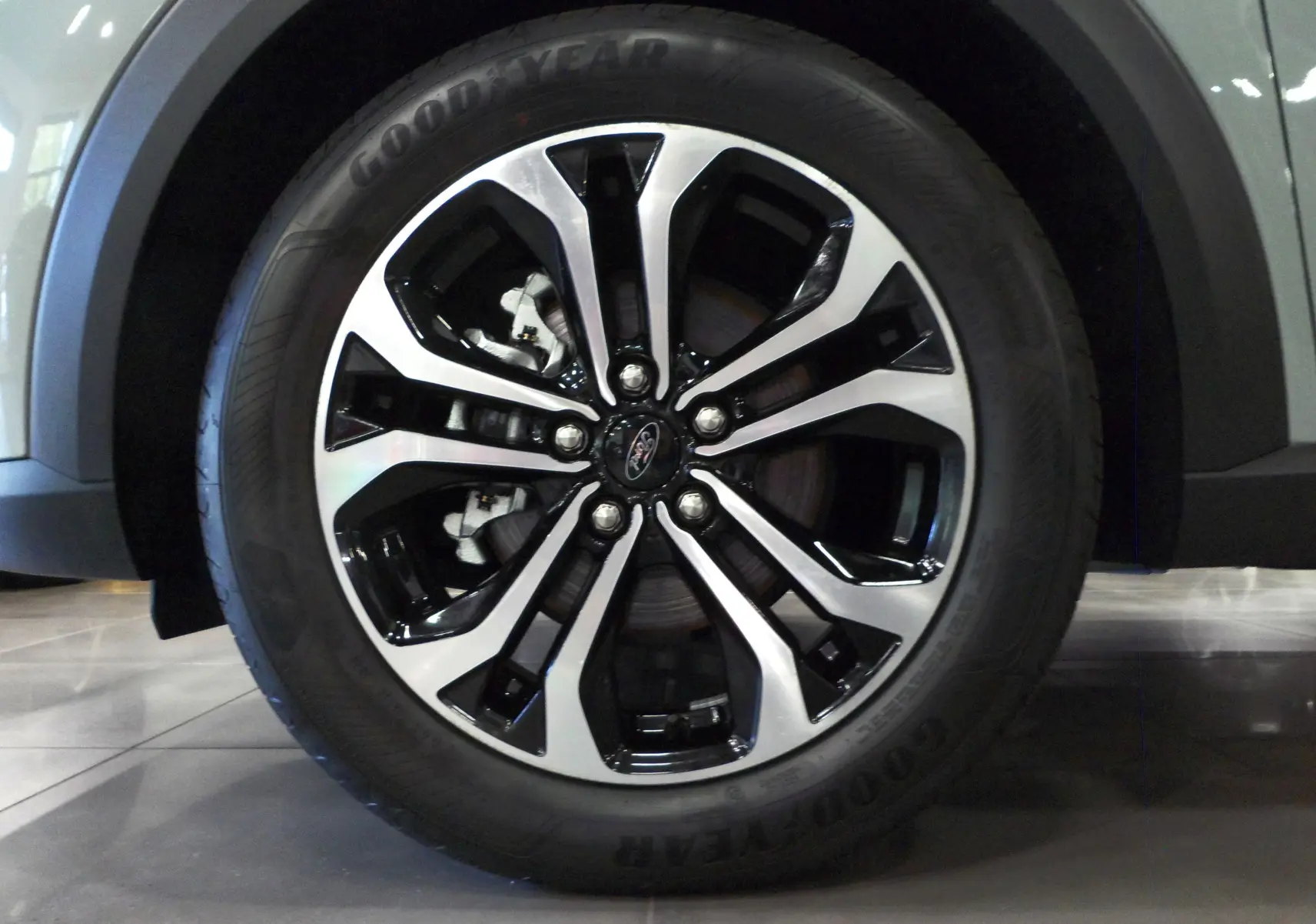 Gros plan sur la jante alliage bicolore du Ford Puma gris Cactus, mettant en valeur le logo Ford central.