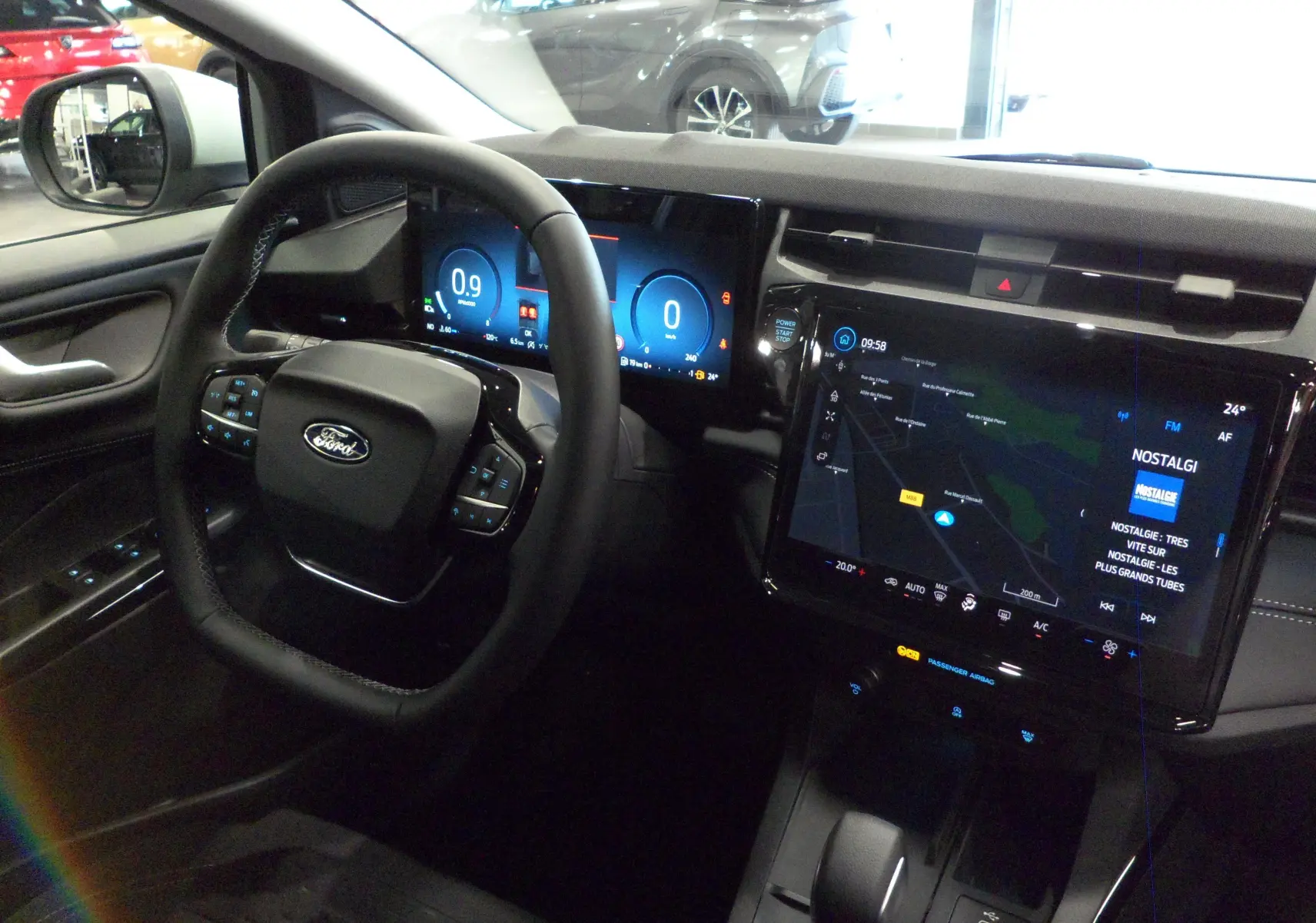 Vue intérieure côté conducteur du Ford Puma 2025 gris, avec tableau de bord numérique et grand écran tactile central allumé.