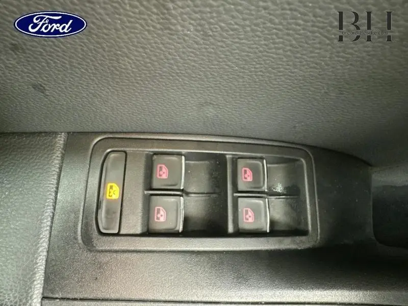 Panneau de commandes des vitres électriques côté conducteur, boutons noirs avec pictogrammes rouges sur fond noir.