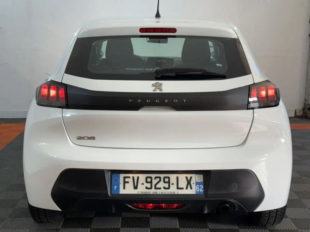Vue arrière d'une Peugeot 208 blanche avec feux arrière allumés et plaque d'immatriculation française visible.