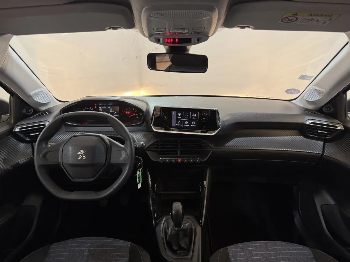 Vue frontale de l'habitacle noir de la Peugeot 208 PureTech 75 S&S Like avec tableau de bord et écran tactile central.
