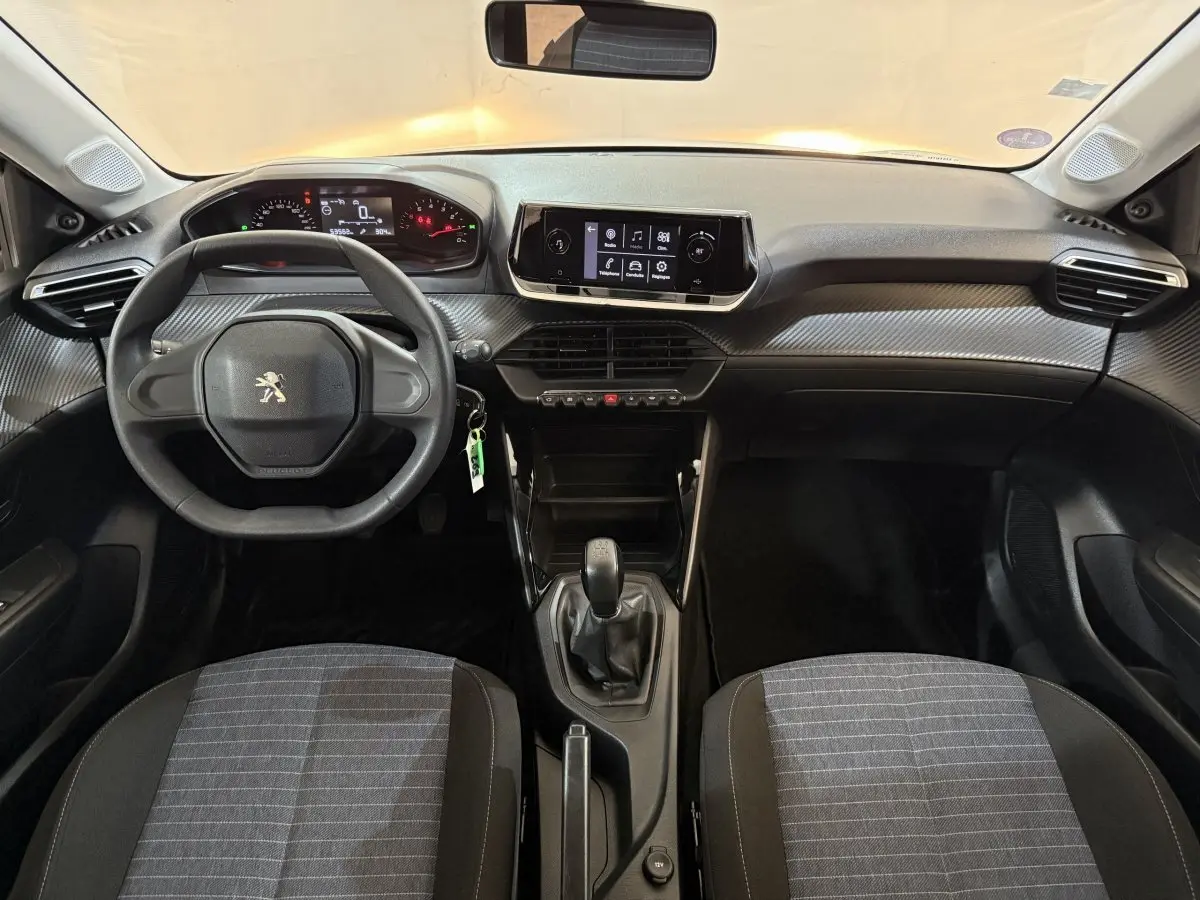 Vue intérieure avant de la Peugeot 208 PureTech 75 S&S Like 2020, tableau de bord noir avec écran tactile central et volant compact.