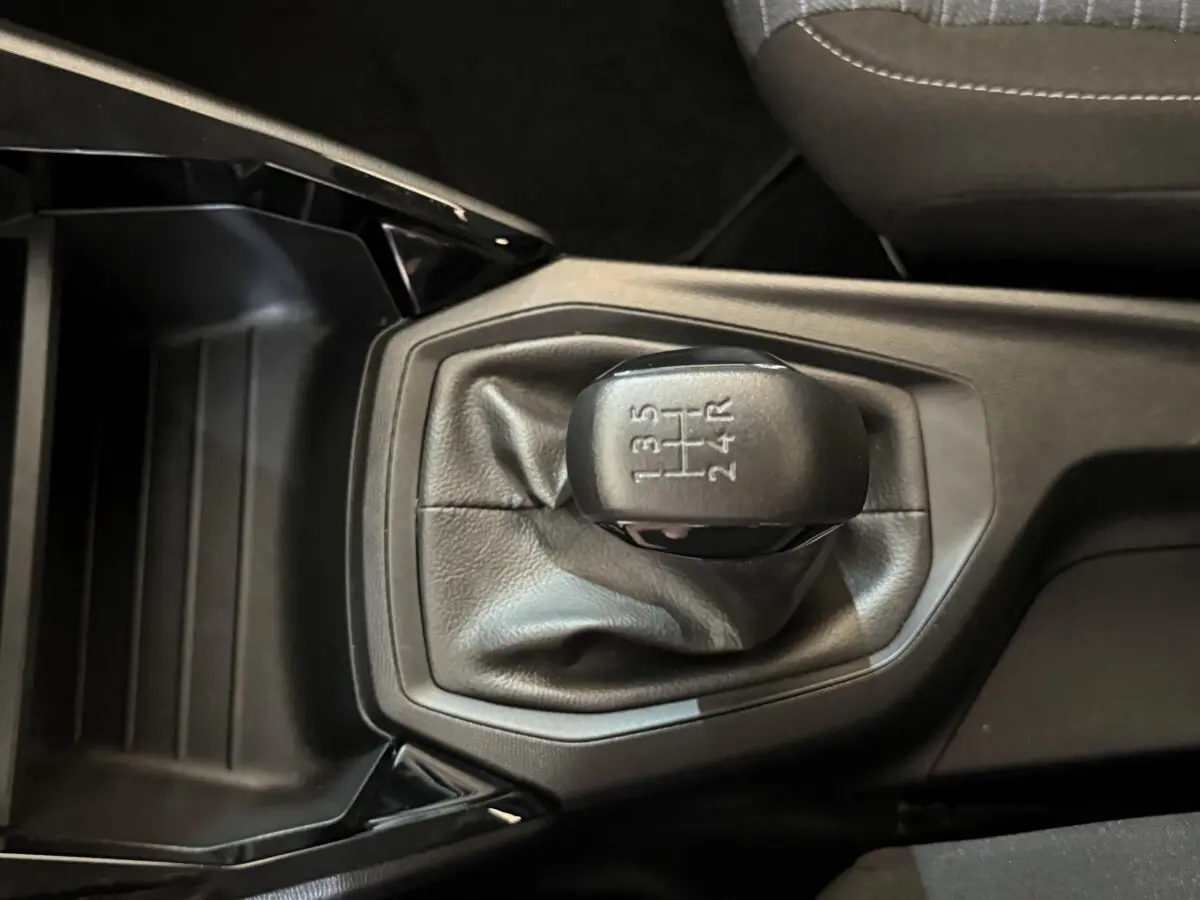 Vue rapprochée du levier de vitesses manuel noir de la Peugeot 208 PureTech 75 S&S Like 2020, intérieur sombre.