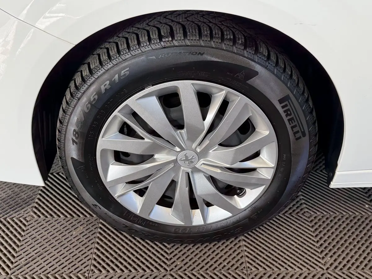 Gros plan sur la roue avant droite d’une Peugeot 208 blanche avec jante argentée et pneu Pirelli.