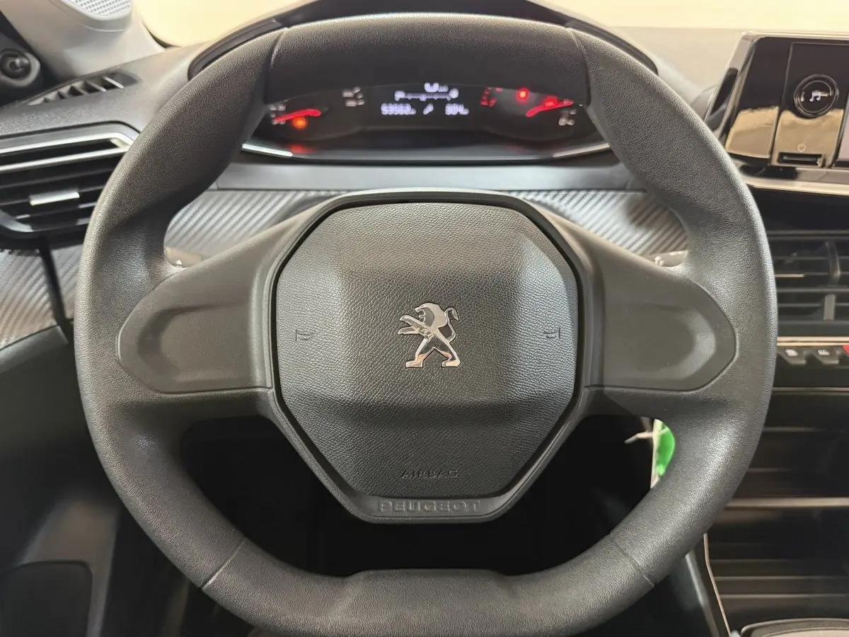 Vue rapprochée du volant noir de la Peugeot 208 PureTech 75 S&S Like avec tableau de bord et commandes visibles.
