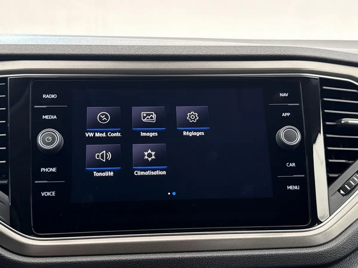 Écran tactile central du tableau de bord du Volkswagen T-Roc 2.0 TDI bleu, affichant les options média et climatisation.