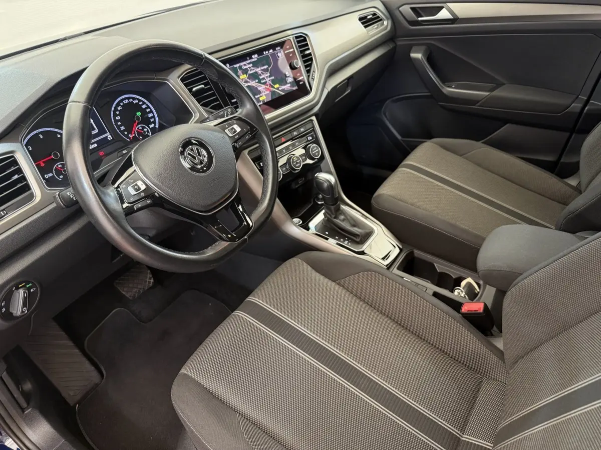 Vue intérieure côté conducteur du Volkswagen T-Roc 2.0 TDI 150, montrant le volant cuir et l’écran tactile central.