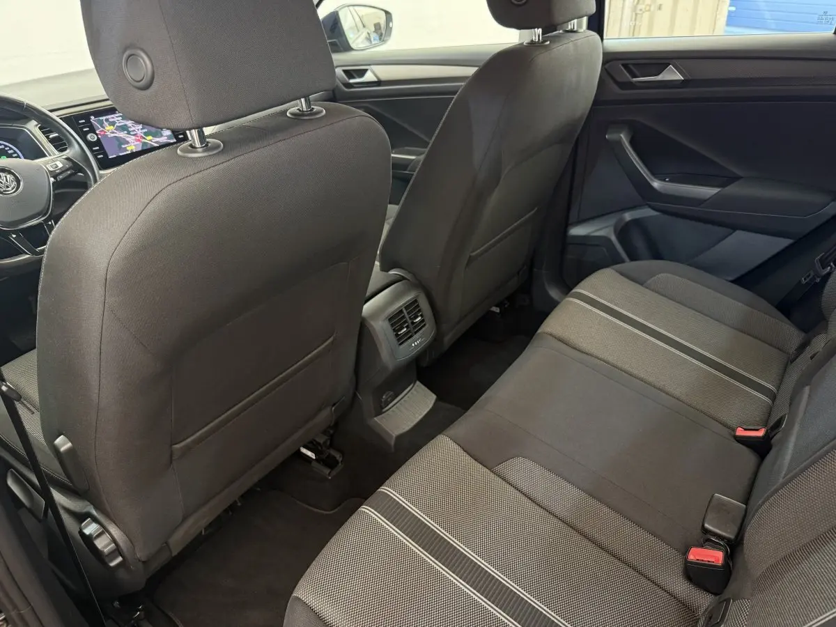 Vue intérieure arrière du Volkswagen T-Roc 2020, sièges tissu noirs avec détails gris et console centrale avec aérateurs.