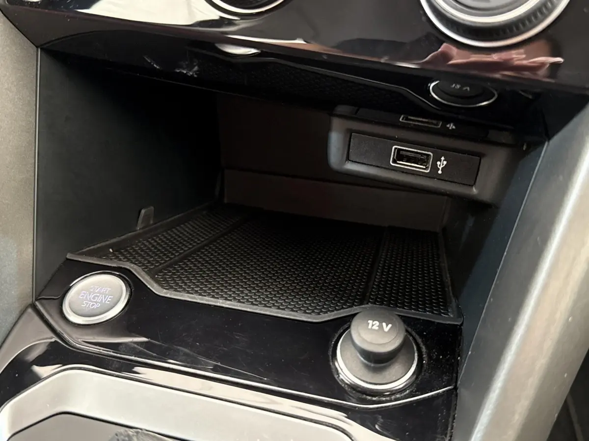 Gros plan intérieur sur la console centrale du Volkswagen T-Roc bleu, montrant bouton start/stop et prise 12V.