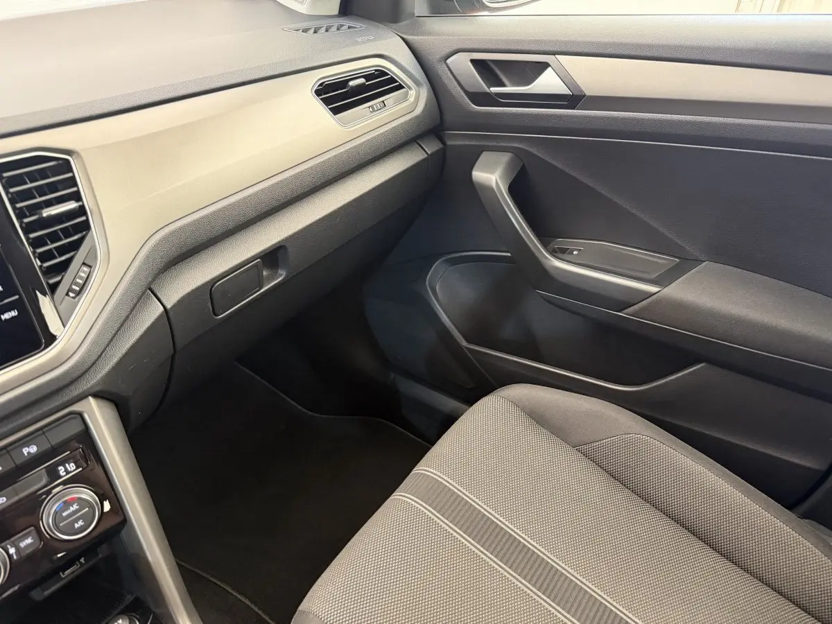 Vue intérieure côté passager du Volkswagen T-Roc 2020, mettant en valeur la sellerie grise et le tableau de bord noir.