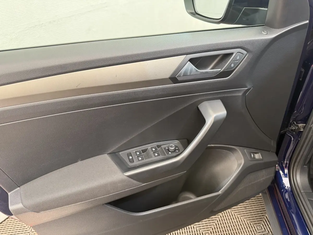Vue intérieure côté gauche de la porte avant d’un Volkswagen T-Roc bleu avec commandes de vitres et rétroviseurs.