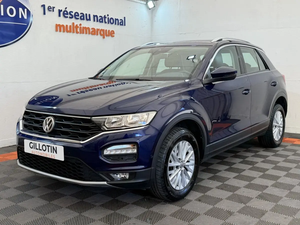 Volkswagen T-Roc bleu en 3/4 avant droit, avec jantes argentées et calandre noire brillante.