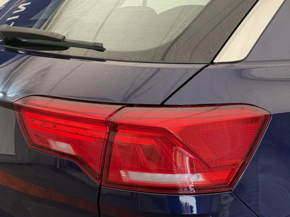 Gros plan sur le feu arrière droit rouge d’un Volkswagen T-Roc bleu 2020 avec toit blanc visible.