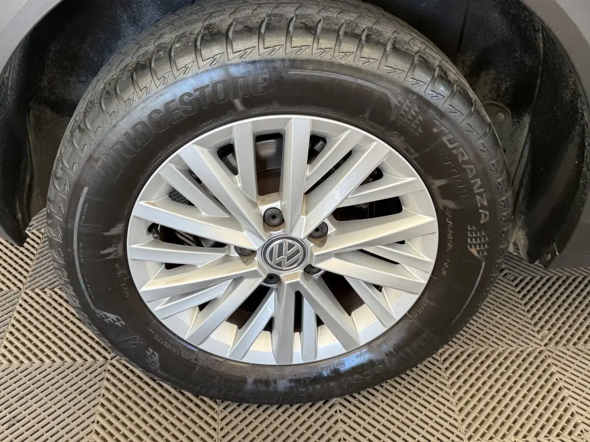 Gros plan sur la roue avant droite d’un Volkswagen T-Roc bleu, avec jante alliage argentée et pneu Bridgestone.
