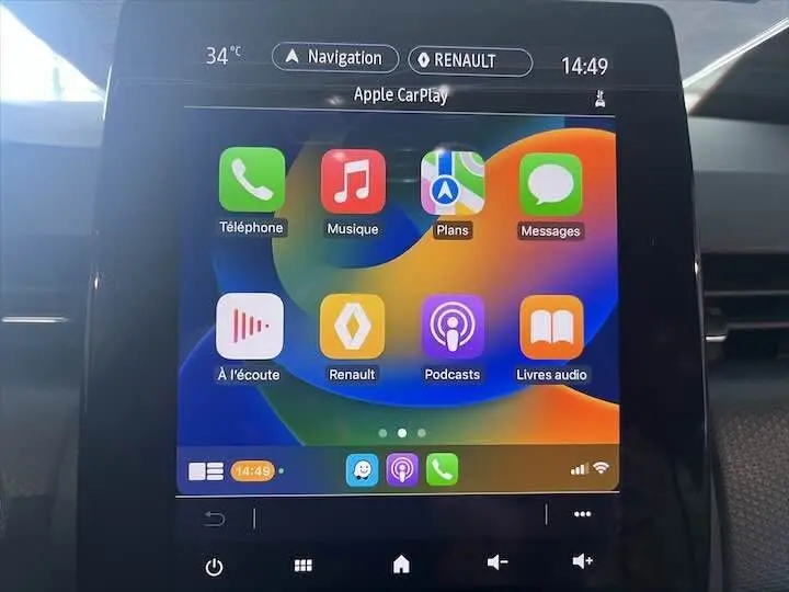 Écran tactile central de la Renault Clio V blanc nacré affichant Apple CarPlay avec icônes colorées en intérieur.