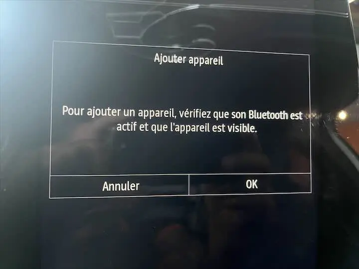 Écran tactile intérieur de Renault Clio V blanc nacré affichant un message d'ajout d'appareil Bluetooth.