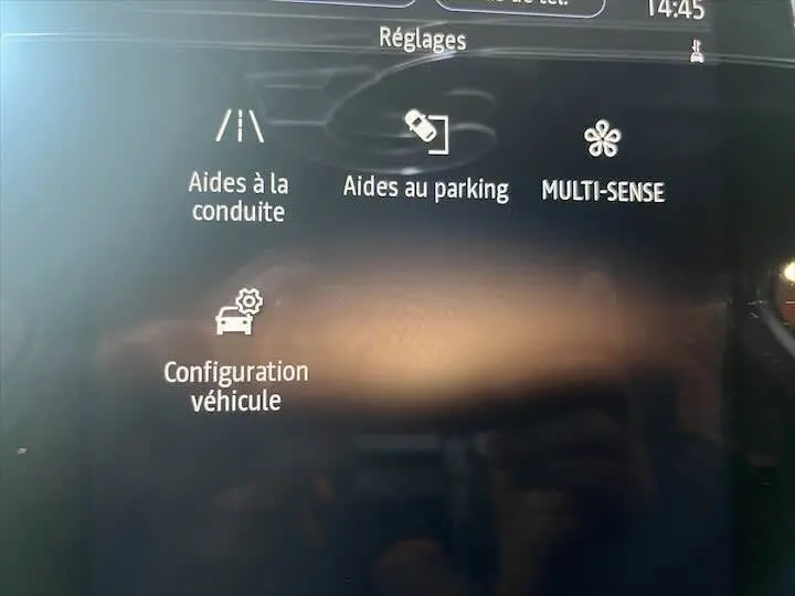 Écran tactile intérieur de la Renault Clio V blanc nacré montrant les réglages d’aides à la conduite et parking.