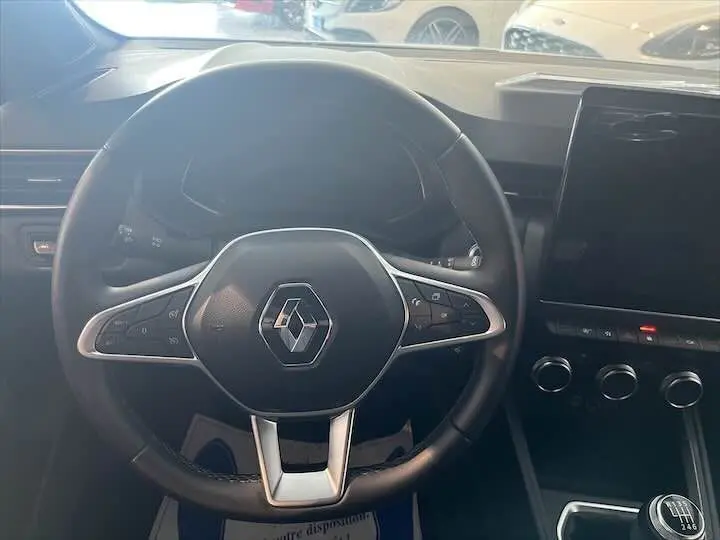 Vue intérieure centrée sur le volant noir de la Renault Clio V 1.0 TCE 90 Intens avec tableau de bord et écran tactile.