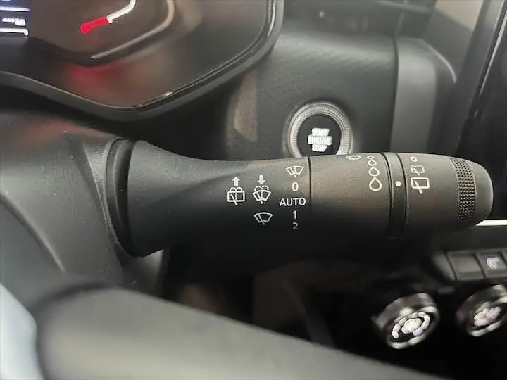 Gros plan sur la commande d'essuie-glace à gauche du volant dans l'habitacle d'une Renault Clio V blanc nacré.