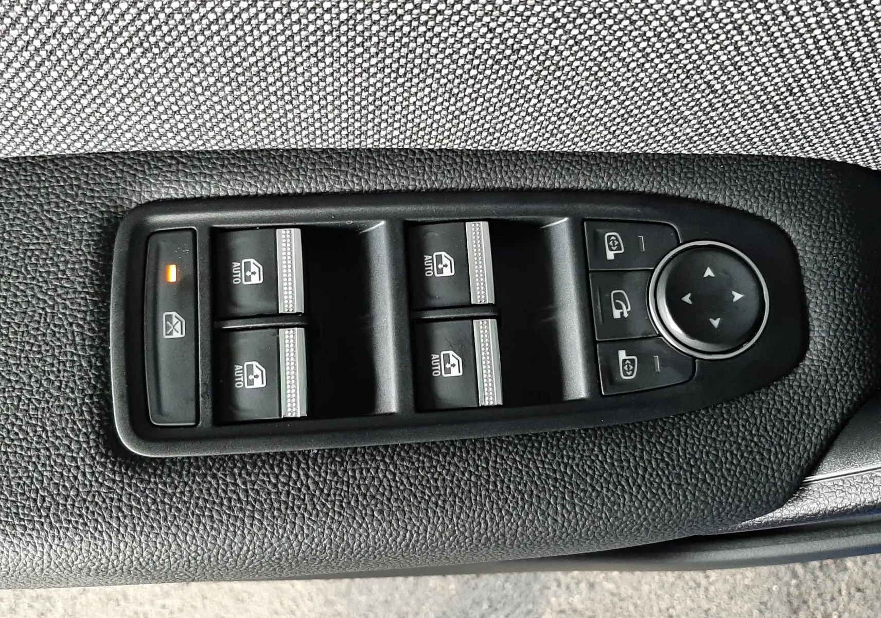 Panneau de commandes des vitres et rétroviseurs sur la porte côté conducteur d'un Renault Captur bleu iron 2024.