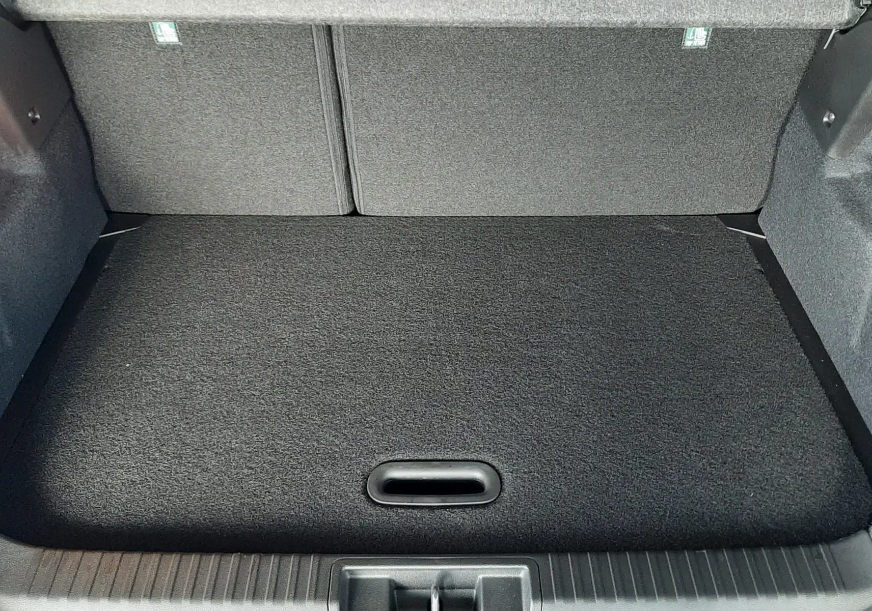 Coffre ouvert du Renault Captur E-Tech Hybrid 145ch Techno 2024 bleu iron avec intérieur noir et plancher plat.