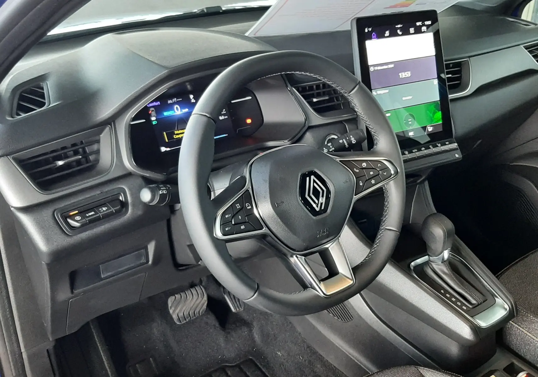 Vue intérieure côté conducteur du Renault Captur E-Tech Hybrid 2024 avec tableau de bord numérique et écran tactile vertical.