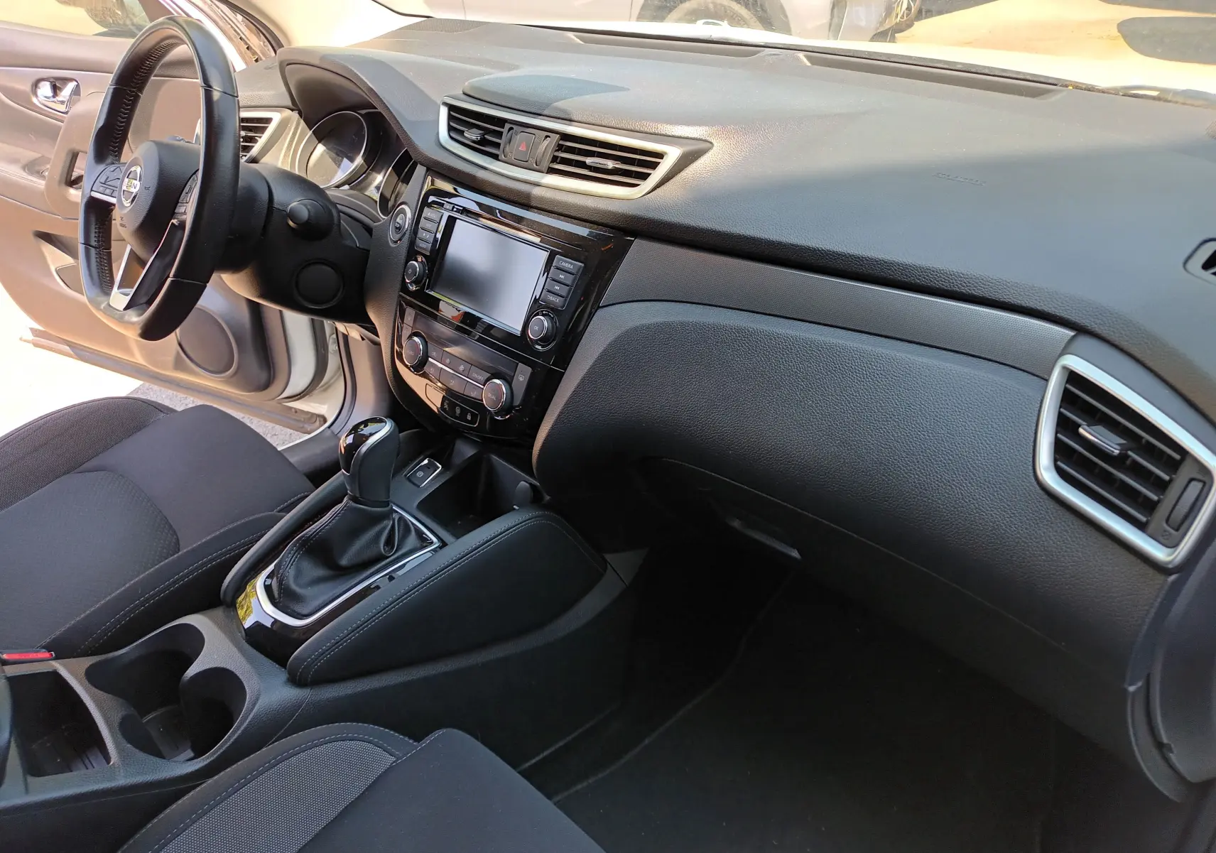 Intérieur du Nissan Qashqai blanc nacré 2019, vue côté conducteur sur tableau de bord et console centrale avec boîte auto.