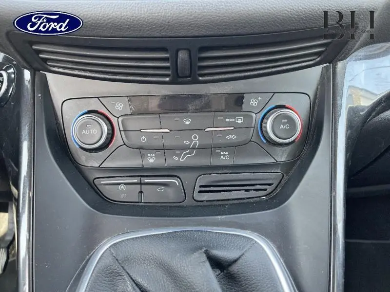 Vue rapprochée de la console centrale du Ford Kuga blanc Glacier 2017, montrant les commandes de climatisation et le levier de vitesse cuir.