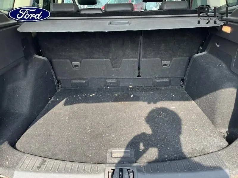 Coffre ouvert d'un Ford Kuga blanc Glacier, montrant l'espace de chargement et la tablette arrière noire.