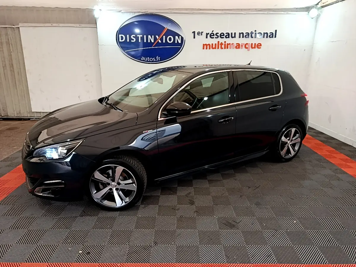 Peugeot 308 1.2 PureTech GT Line gris foncé vue de profil côté gauche en intérieur showroom avec logo Distinxion.