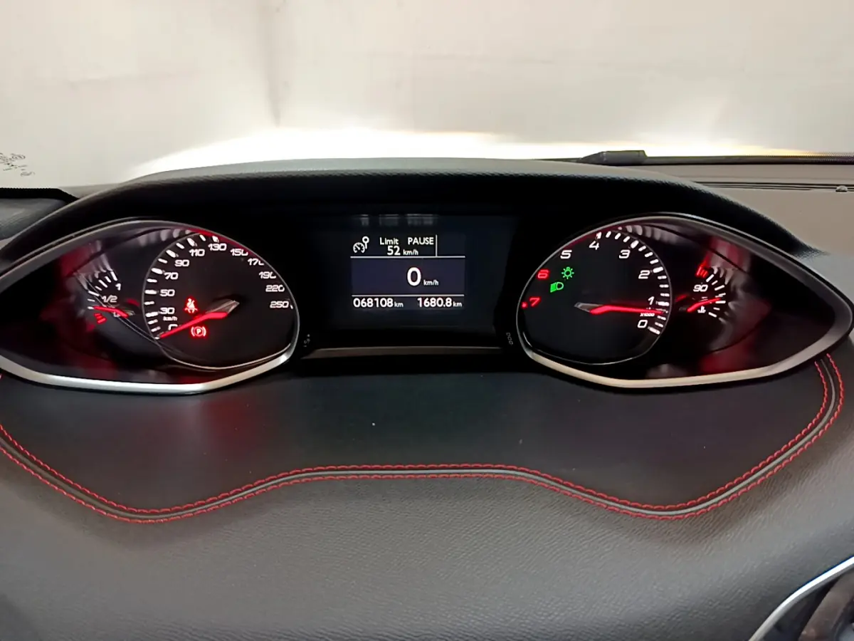 Tableau de bord noir avec surpiqûres rouges de la Peugeot 308 GT Line 2016, affichage digital et compteurs analogiques.