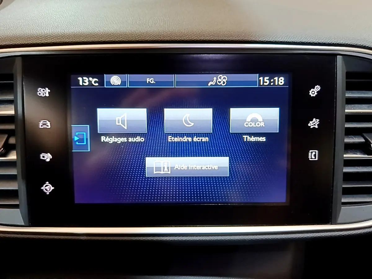Écran tactile central affichant les réglages audio et thèmes dans l'habitacle d'une Peugeot 308 gris foncé de 2016.