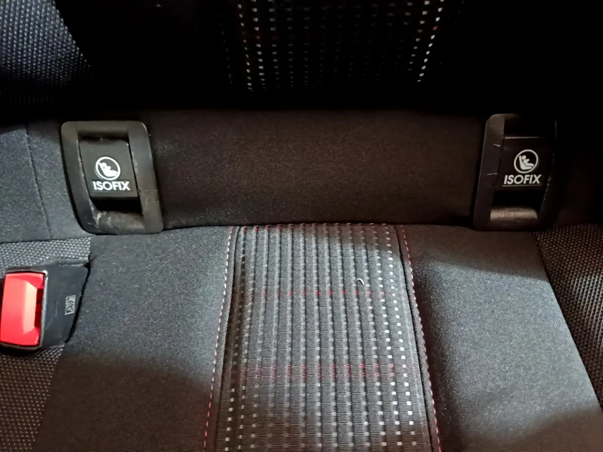 Gros plan sur la banquette arrière noire de la Peugeot 308 avec fixations ISOFIX et couture rouge visible.