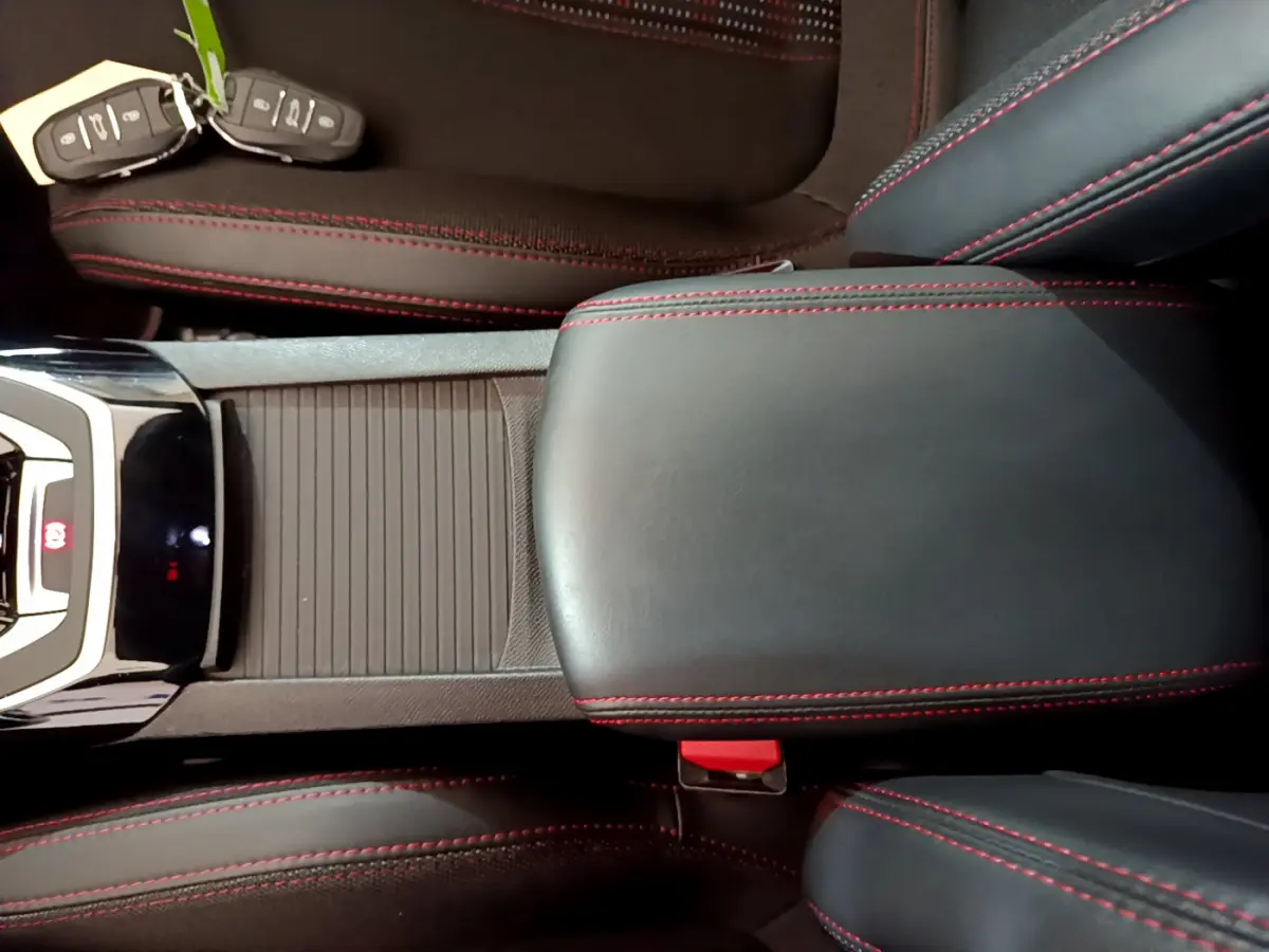 Vue rapprochée de la console centrale et accoudoir en cuir noir avec surpiqûres rouges d'une Peugeot 308 GT Line 2016.