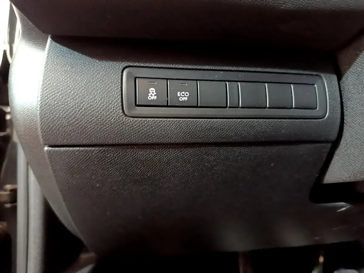Gros plan sur les boutons de contrôle de stabilité et mode éco dans l'habitacle noir d'une Peugeot 308 GT Line 2016.