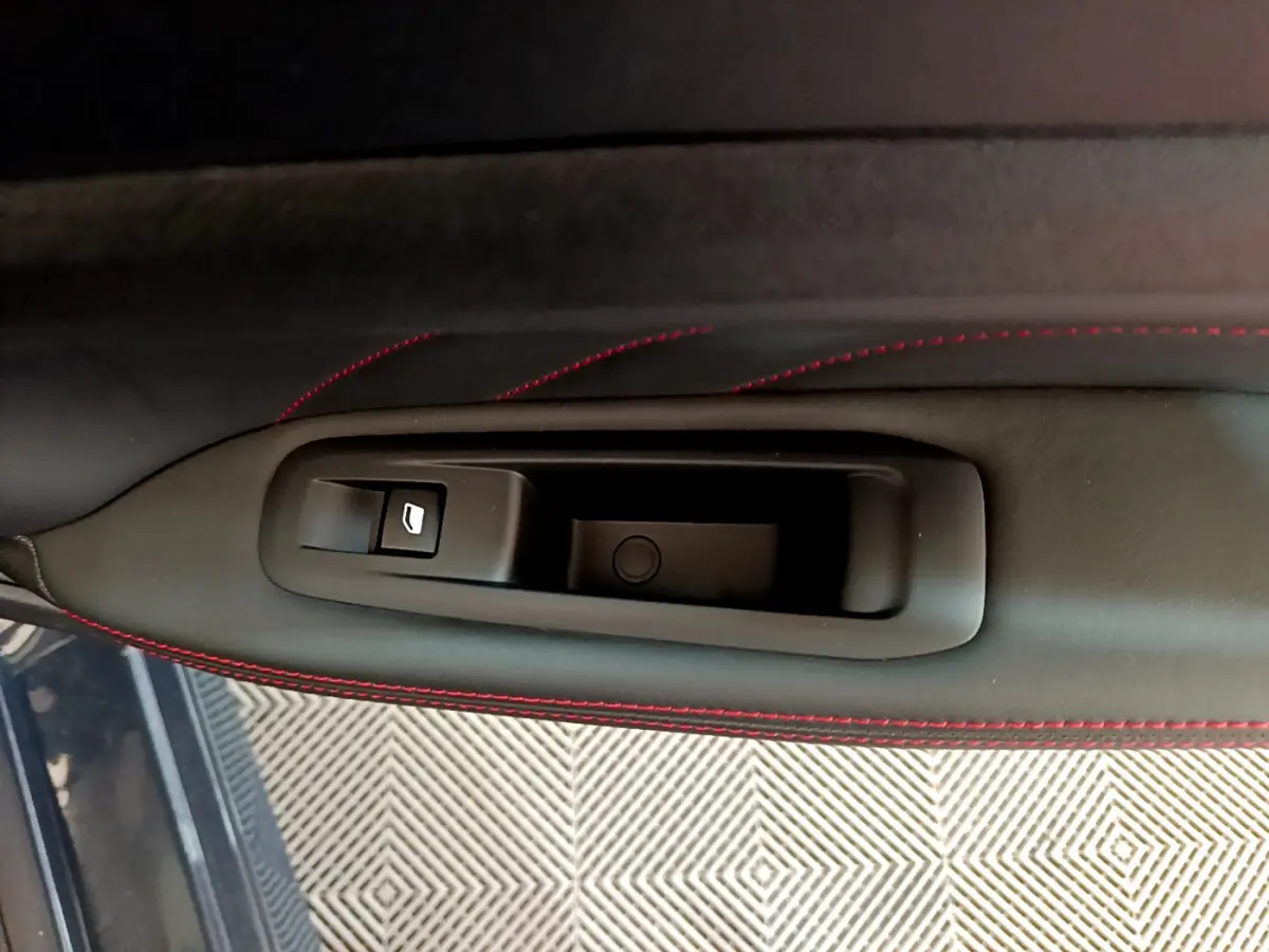 Détail de la poignée intérieure côté gauche avec bouton de lève-vitre sur porte en cuir noir et surpiqûres rouges Peugeot 308 GT Line.