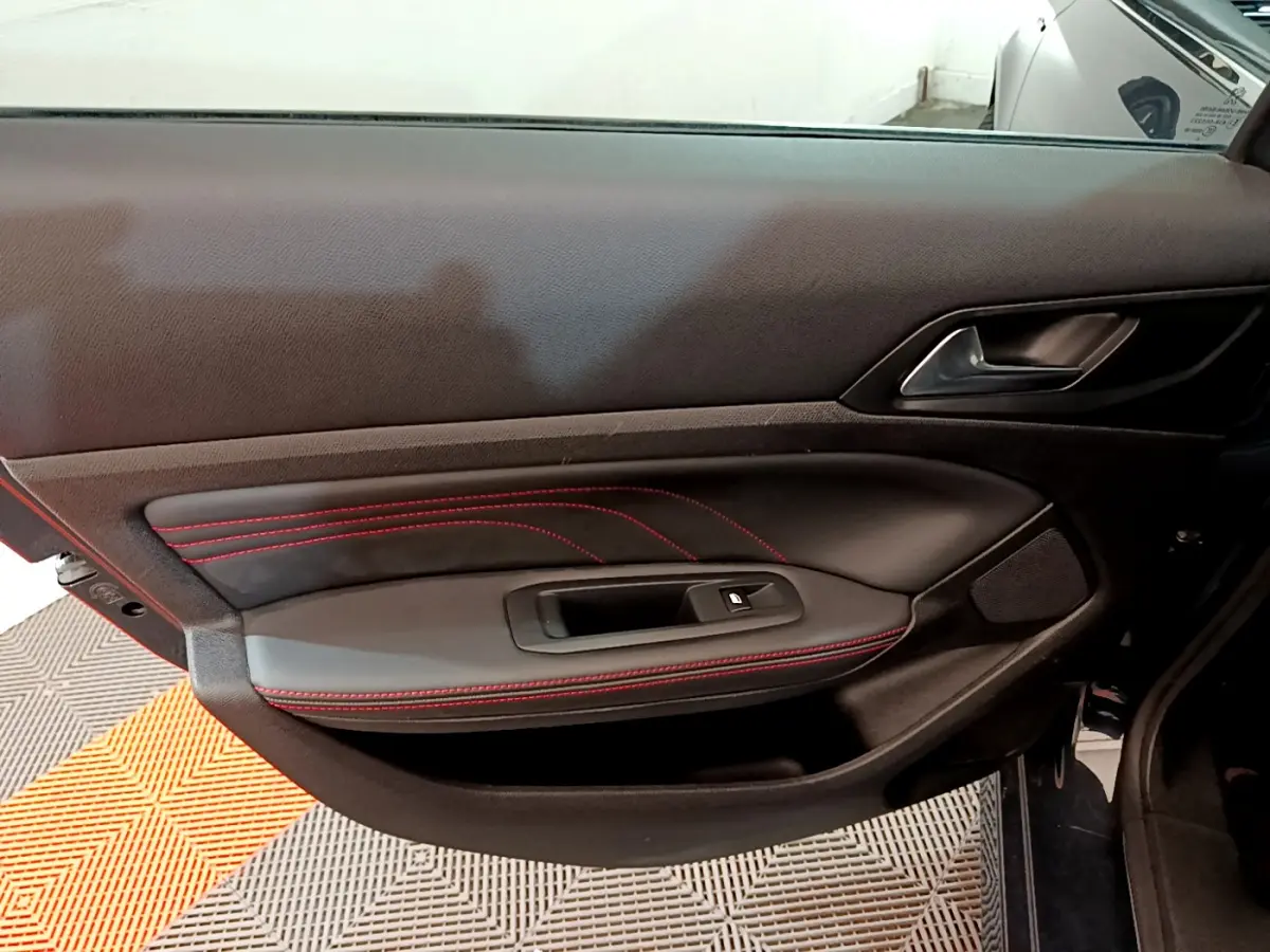 Porte intérieure côté gauche de Peugeot 308 GT Line 2016 en cuir noir avec surpiqûres rouges et poignée métal.